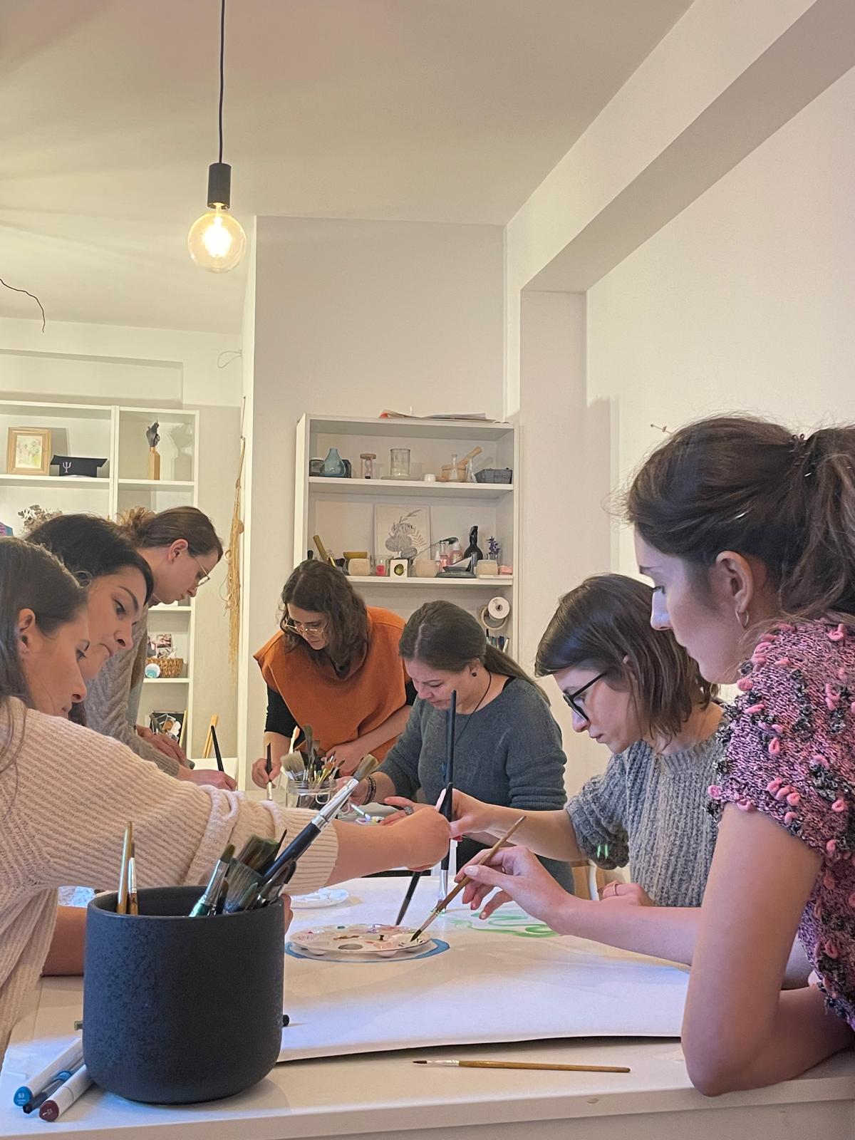 Participante pictând împreună pe o foaie mare, în atelierul MindfulArt®