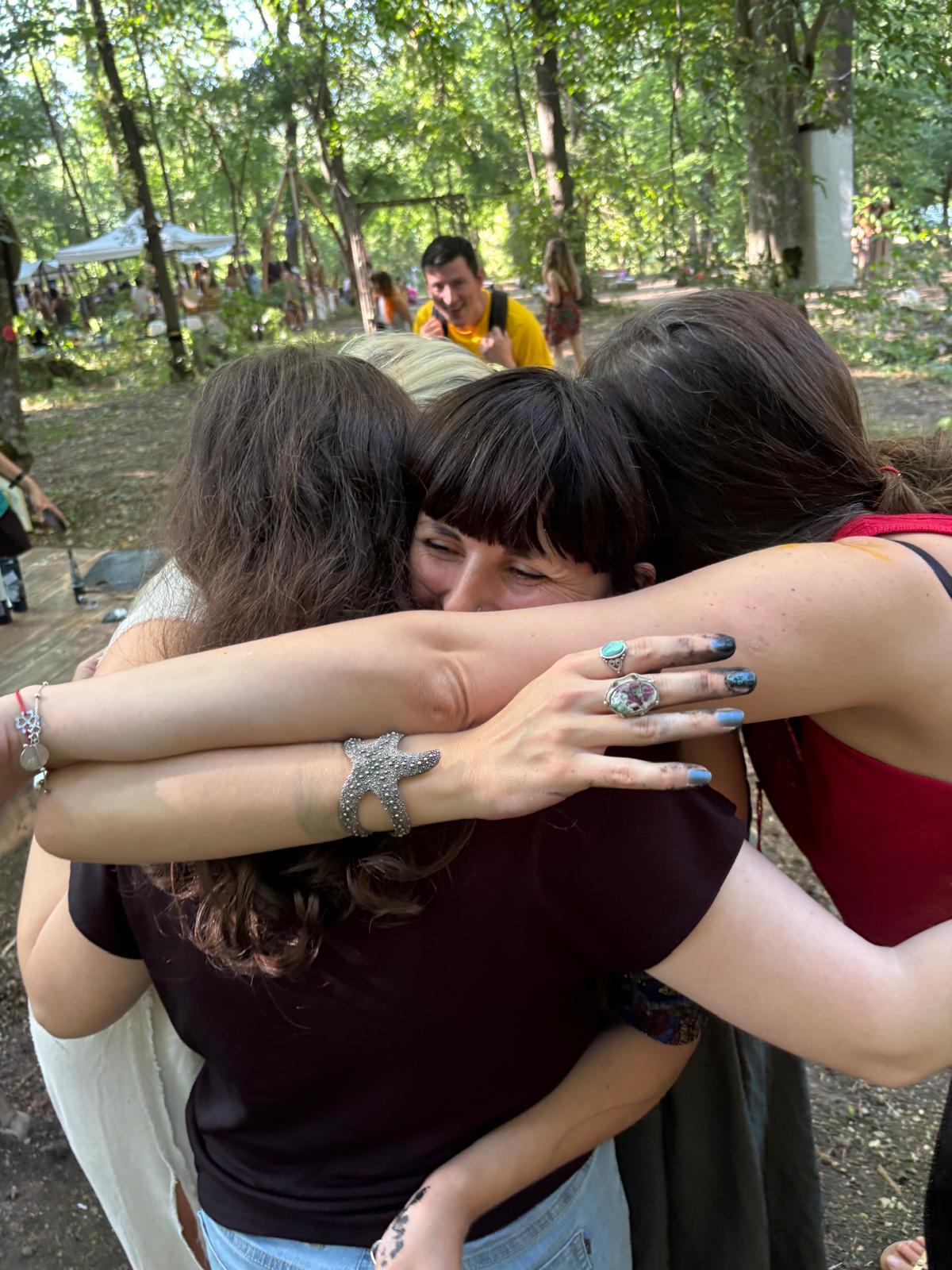 Îmbrățișare de grup între participante, în aer liber